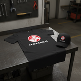 Classic Holden logo T-shirt and matching cap displayed together on a motorsport pit-garage workbench